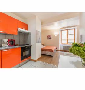 a kitchen with orange cabinets and a bed in a room at Location F1 neuf centre historique Riom (63) - Puy-de-Dôme, Auvergne in Riom