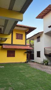 a yellow and white house with a green yard at Pousada Cordel de Itaúnas in Itaúnas