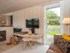 a living room with a desk with a tv and a fireplace at 6 person holiday home in Glesborg in Bønnerup