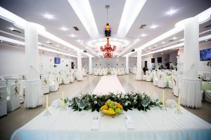 a banquet hall with white tables and white chairs at Julton Events Hotel in Domje