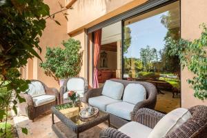 a patio with wicker chairs and a couch and a table at Villa près de golfs in Marrakech