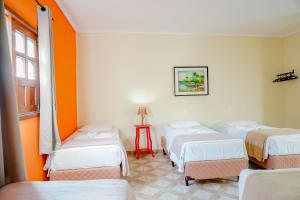 4 camas en una habitación con paredes de color naranja en Pousada Kabana de Pedra en Ibicoara