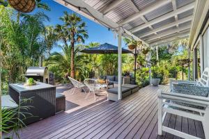 a wooden deck with a grill and an umbrella at Tamborine Palms Farmhouse in Tamborine