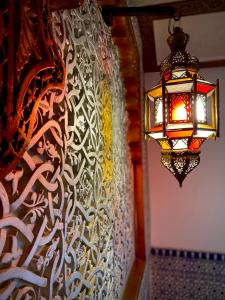 una lámpara colgada de una pared con una pared estampada en Riad Najiba en Rabat