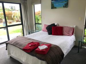 a bedroom with a large bed with two red pillows on it at Silverdale Garden Stay in Orewa