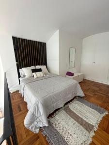 a white bedroom with a large bed and a rug at Soleado MDP in Mar del Plata