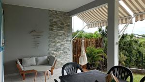 un patio con sofá, mesa y sillas en T2 jardin clos Les Nids de la Colline en Saint-François