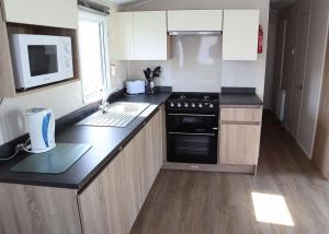 a kitchen with a stove and a sink and a microwave at Coastfields Holiday Village in Ingoldmells