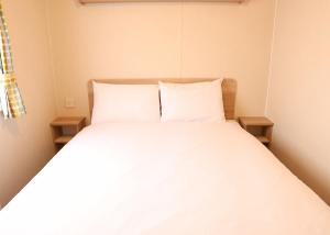 a bed with white sheets and pillows in a room at Coastfields Holiday Village in Ingoldmells