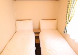 two beds in a small room with a window at Coastfields Holiday Village in Ingoldmells