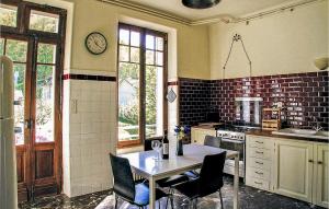 eine Küche mit einem Tisch und Stühlen sowie einer Uhr an der Wand in der Unterkunft Amazing Home In Terrasson-Lavilledieu in Terrasson