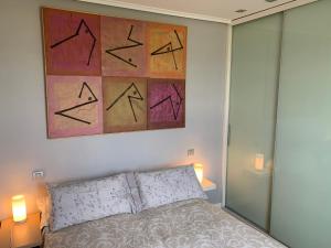 Un dormitorio con una cama con una pintura encima. en Apartamento Puerto Deportivo Marina de Santander, en Santander