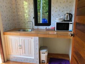 eine kleine Küche mit einer Spüle und einer Mikrowelle in der Unterkunft Lanta Living bungalow in Ko Lanta