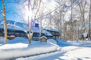 a train is traveling through a snow covered forest at Hotel Wohnen in Hakuba