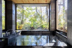 a bathroom with a large window and a bath tub at Hotel Wohnen in Hakuba