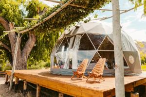 - deux chaises sur une terrasse en bois avec une tente en forme de dôme dans l'établissement Domos Uspallata, à Uspallata