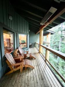 a porch of a cabin with two chairs and a dog sitting at Ski In/Ski Out Luxury Home w/ jacuz/ fireplace in Whistler