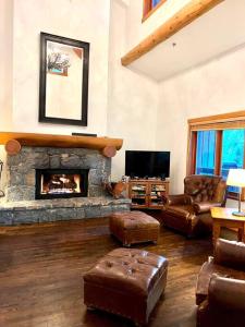 a living room with a fireplace and leather furniture at Ski In/Ski Out Luxury Home w/ jacuz/ fireplace in Whistler