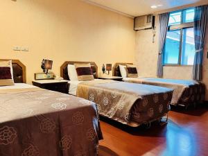 una camera d'albergo con tre letti e una finestra di Shinyes Motel a Su-ao