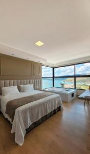a bedroom with a large bed and large windows at Vista do Lago Hotel in Capitólio