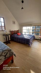 a bedroom with two beds and a table and windows at Casa de Campo Villa Angélica Lunahuaná in Lunahuaná