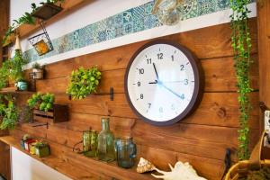 a clock is on a wooden wall with plants at Bunzo Rezort 今帰仁 in Shushi