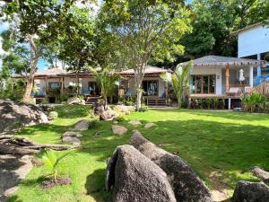 a house with rocks in front of a yard at Siam Cookies Cottage in Haad Pleayleam