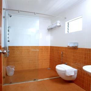 een badkamer met een douche, een toilet en een wastafel bij Hotel Aiswarya in Cochin