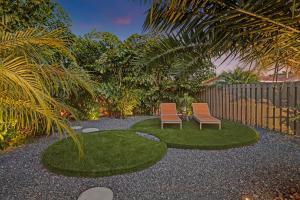 two chairs in a yard with grass and a fence at Stylish Luxury Tropical Junior Suite in Fort Lauderdale
