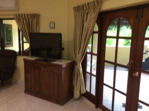 un soggiorno con TV a schermo piatto accanto a una porta di P&B guesthouse a Na Jomtien