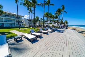 a row of chaise lounges and benches on the beach at Panoramic Views Two Decks 1st Row Ocean Kite Beach in Cabarete +13 photos