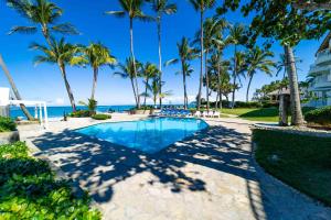 uma piscina com palmeiras e o oceano em WOW location Kite Beach Oceanfront Panoramic Views 2 DECKS 2 Bedrooms em Cabarete