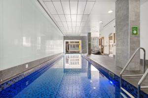 a swimming pool in a building with a tile floor at Morphett City Chic 1 bdrm Kitchen Wifi Pool in Adelaide