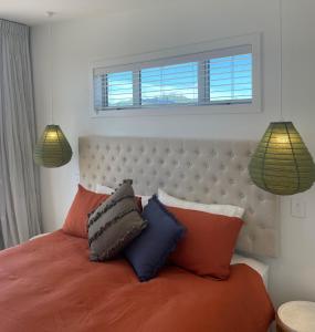 um quarto com uma cama com almofadas e uma janela em Sublime Nooks em Havelock North