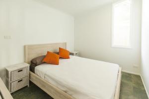 a bedroom with a bed with orange pillows on it at Drift Beach House Getaway in Holloways Beach