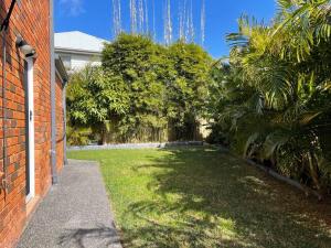 un patio con un edificio de ladrillo rojo y árboles en Cheerful 4-bedroom family retreat in Caves Beach, en Caves Beach