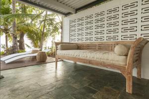 a couch sitting on a porch with a wall at Drift Beach House Getaway in Holloways Beach