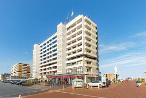 a tall white building with cars parked in a parking lot at Strandnah in Westerland (Sylt)