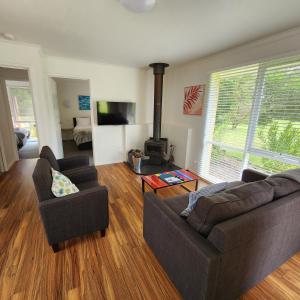 a living room with two couches and a fireplace at Bells Beach Cottages - Pet friendly cottage with wood heater in Torquay