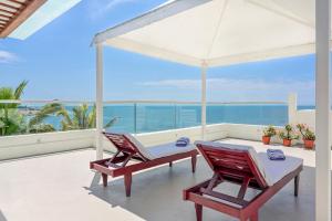 een patio met 2 stoelen en een tafel op een balkon bij Rockholm at the Light House Beach in Kovalam