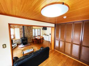 白馬的住宿－Cottage Hotel Fenice Hakuba，客厅设有黑色沙发和木制天花板