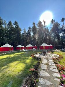 un groupe de tentes rouges et blanches dans un champ dans l'établissement The Glamping Spot Kalam, à Kalām