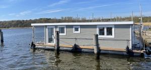 uma casa sobre uma doca sobre um corpo de água em Hausboot Janne Lübeck Inclusive Kanu nach Verfügbarkeit SUP und WLAN 50 MBit s Flat em Lübeck