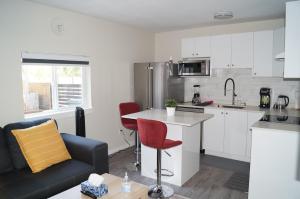 una cucina e un soggiorno con armadi bianchi e sedie rosse di Ground Level One Bedroom Suite a Surrey