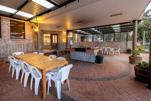 a patio with a wooden table and white chairs at BIG4 Mudgee Holiday Park in Mudgee