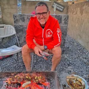 a man is cooking food on a grill at Jabal Shams Mountain Rest House in Al Hūb