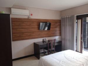 Schlafzimmer mit einem Bett, einem Schreibtisch und einem TV in der Unterkunft NEW KUBU DI BUKIT in Jimbaran