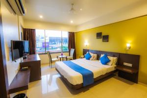 ein Hotelzimmer mit einem Bett und einem TV in der Unterkunft Hotel Solitaire in Pune