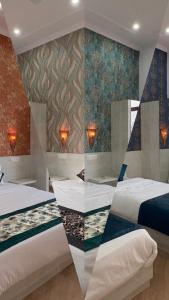 La Curcuma Luxury Homestay في خاجوراهو: غرفه فندقيه سريرين وجدار
