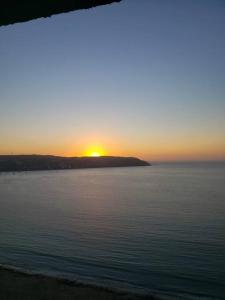a sunset over a body of water with the sun setting at Apartamento junto a la playa en Bahía Horizonte in Coquimbo